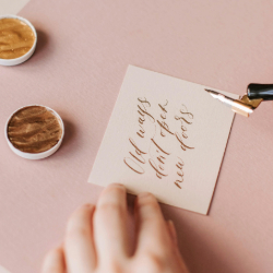 Close-up of hands writing calligraphy on a greeting card